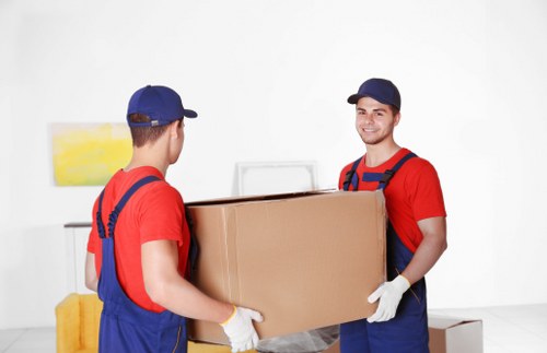Professional piano movers handling an upright piano in a Brompton home