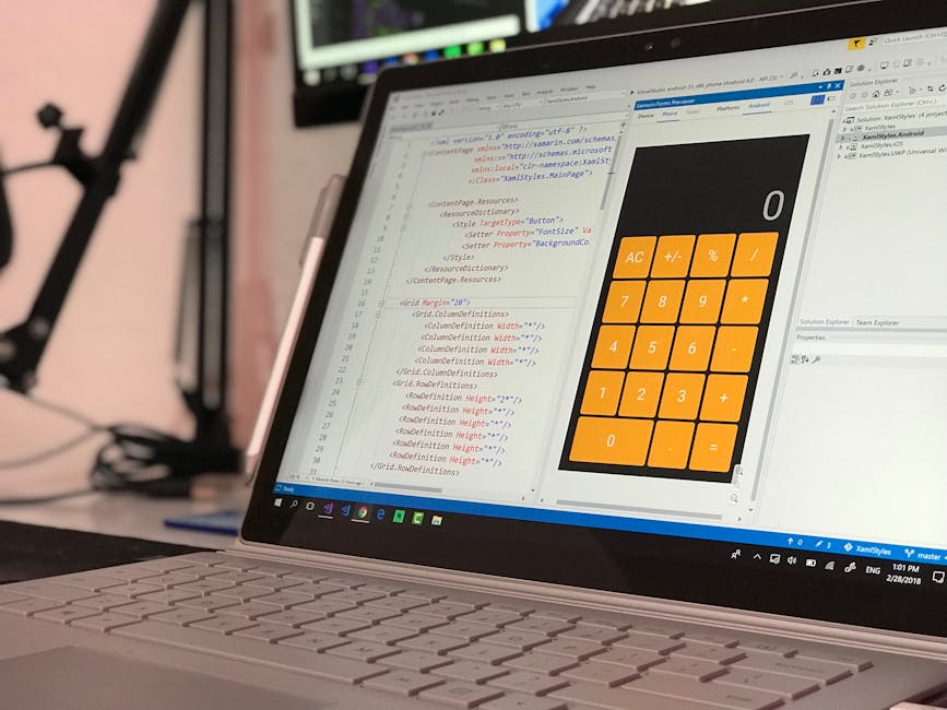 A close-up of a laptop computer displaying a coding environment with lines of HTML and CSS on the screen, alongside a digital calculator interface featuring large orange buttons for basic arithmetic f